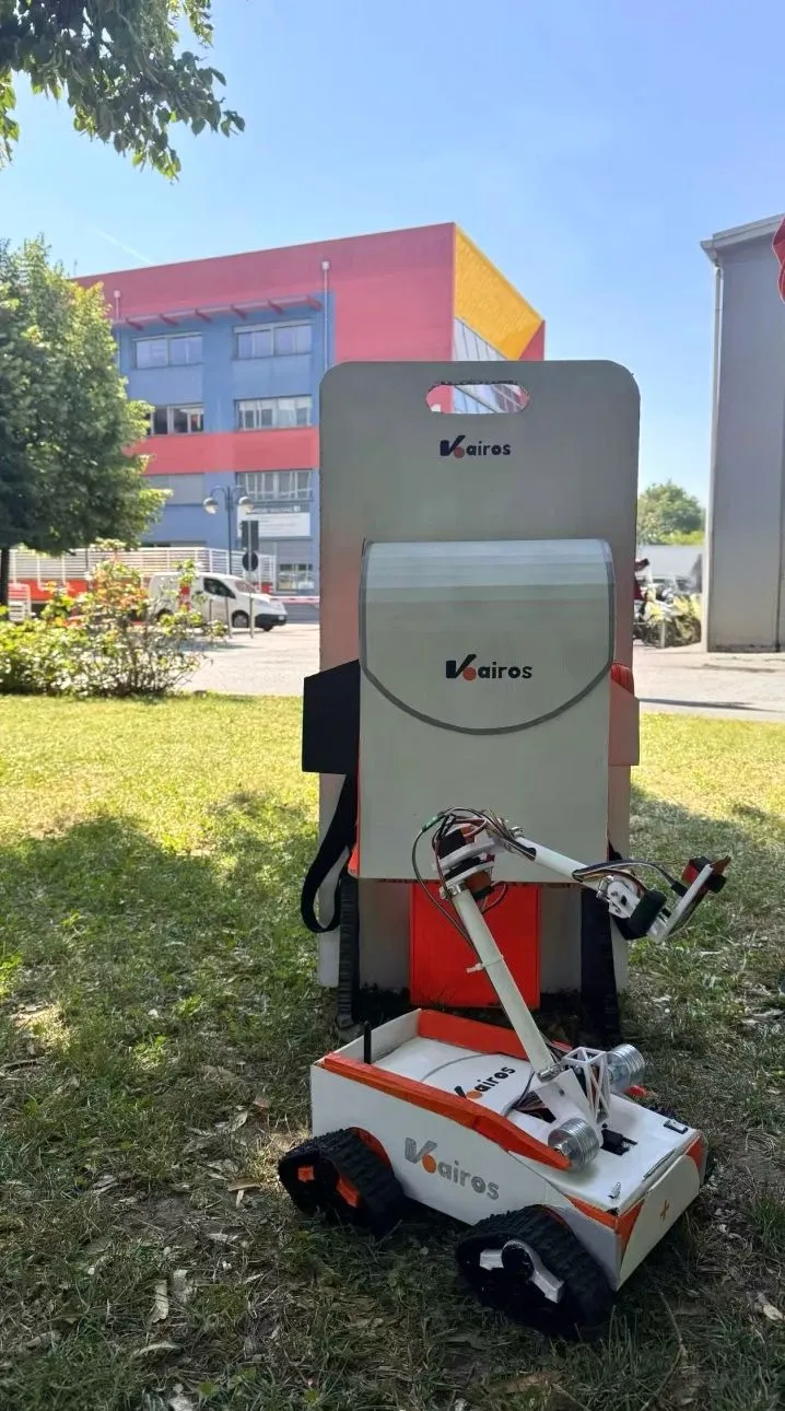 The robot on the grass in front of its carrying case, outside building B1