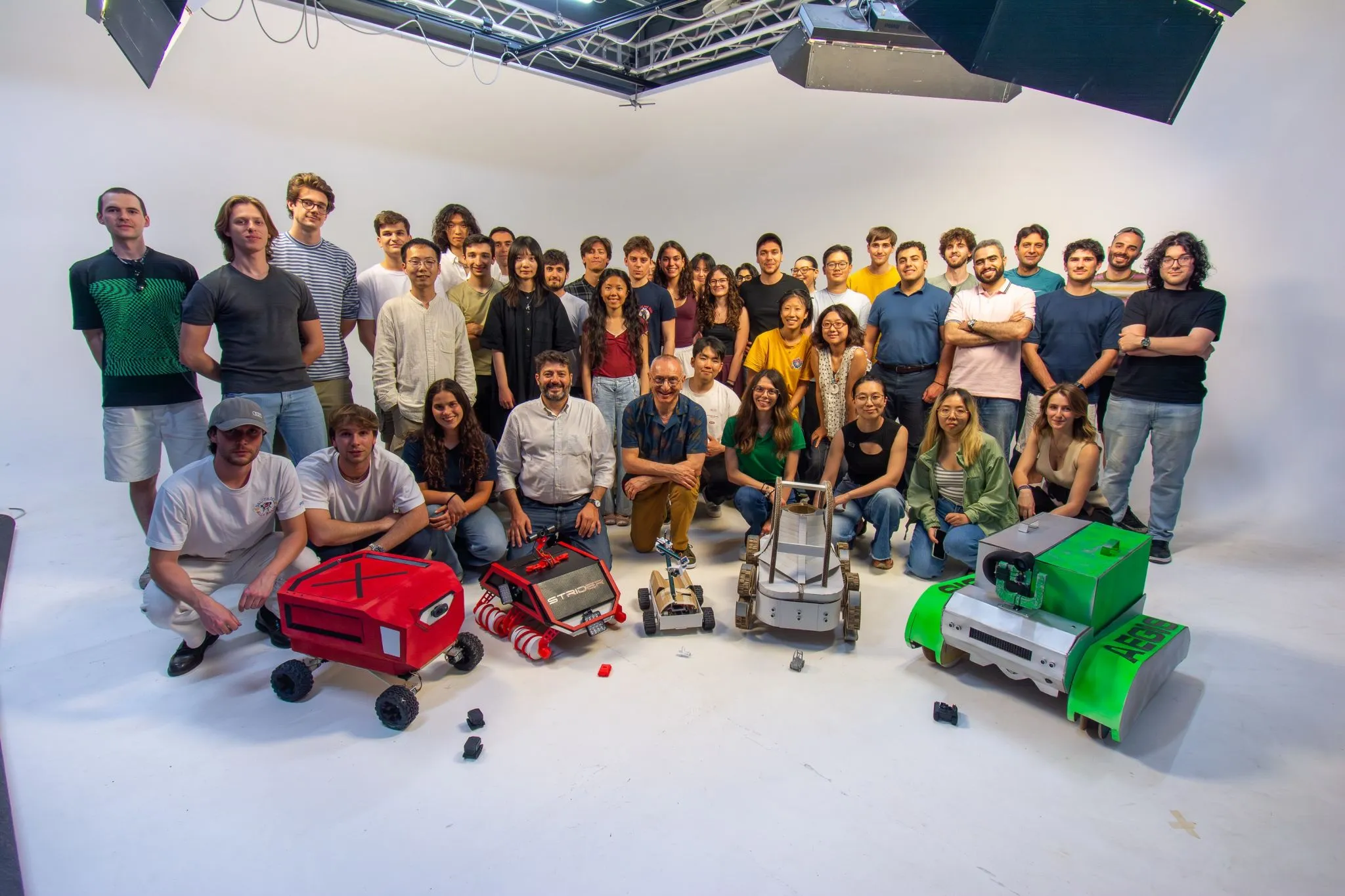 The whole cohort in a photo studio with every team’s robot